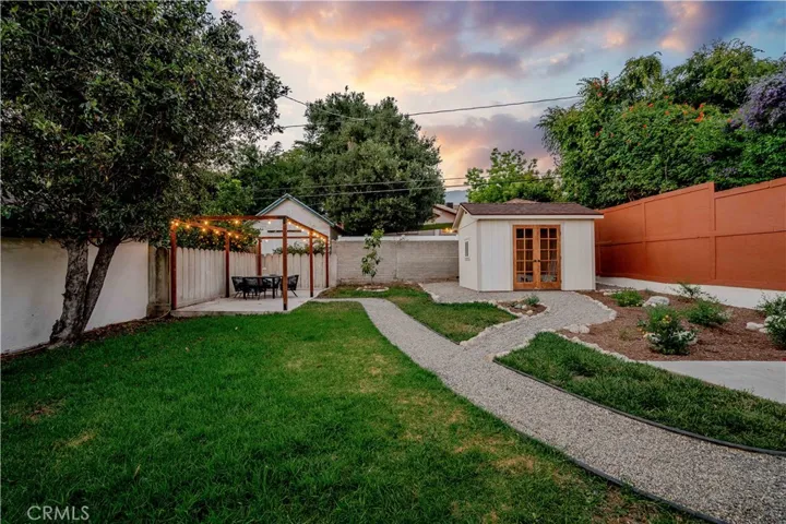 Twilight photo of the back yard with storage shed and lighted deck