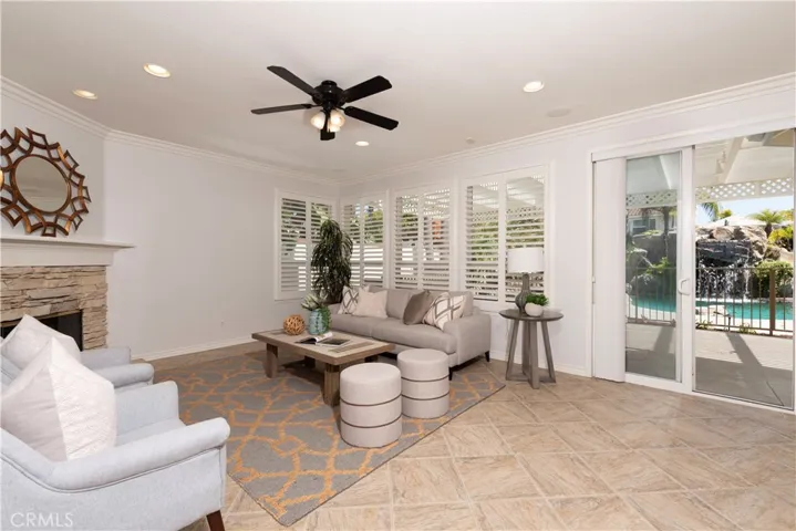 Family Room with Stone-faced Fire Place, Wood Shutters, lighted Celling Fan and slider leading to The Magnificent back Yard