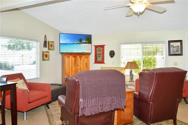 Spacious living room open to the dining area and kitchen with vaulted ceilings, tile floor, ceiling fan drywall-style walls for a modern feeling.