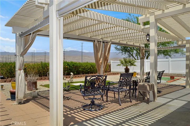 Back to that amazing backyard! Multiple covered patio provide the perfect spot to relax and enjoy the sweeping panoramic views of the desert landscape with distant mountains beyond with tall fences on both sides for privacy, artificial turf for your furry friends, easy-care rock scape, select greenery, and two large storage sheds which create a nook for the smaller patio