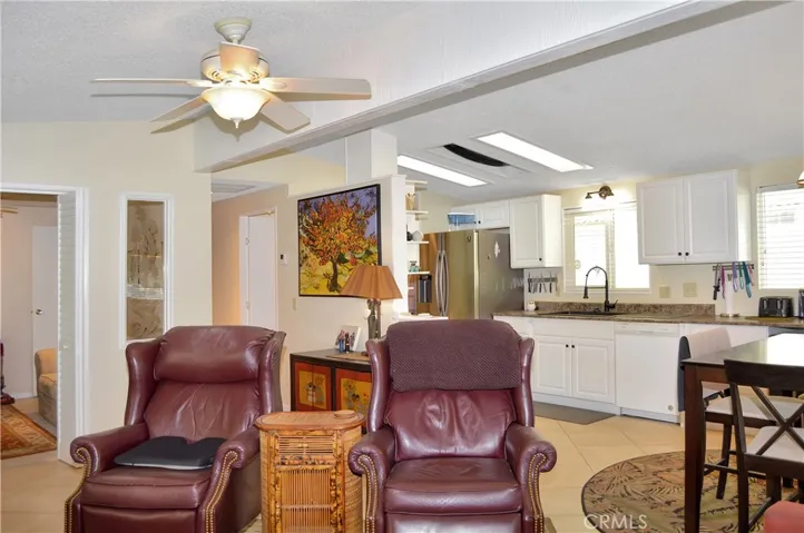 Spacious living room open to the dining area and kitchen with vaulted ceilings, tile floor, ceiling fan drywall-style walls for a modern feeling.
