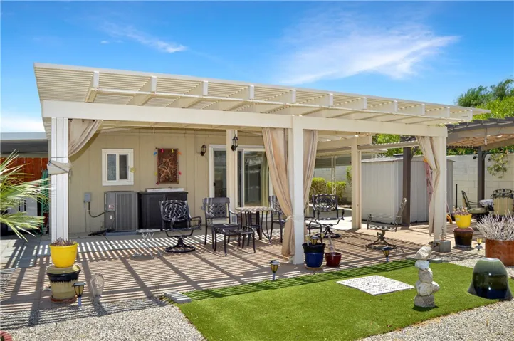 Back to that amazing backyard! Multiple covered patio provide the perfect spot to relax and enjoy the sweeping panoramic views of the desert landscape with distant mountains beyond with tall fences on both sides for privacy, artificial turf for your furry friends, easy-care rock scape, select greenery, and two large storage sheds which create a nook for the smaller patio