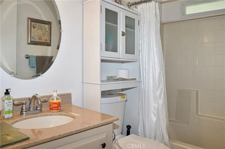 The 2nd bath has an attractive vanity, round mirror, and full-size tub/shower combo