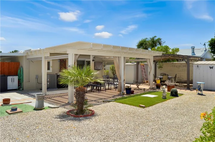 Back to that amazing backyard! Multiple covered patio provide the perfect spot to relax and enjoy the sweeping panoramic views of the desert landscape with distant mountains beyond with tall fences on both sides for privacy, artificial turf for your furry friends, easy-care rock scape, select greenery, and two large storage sheds which create a nook for the smaller patio