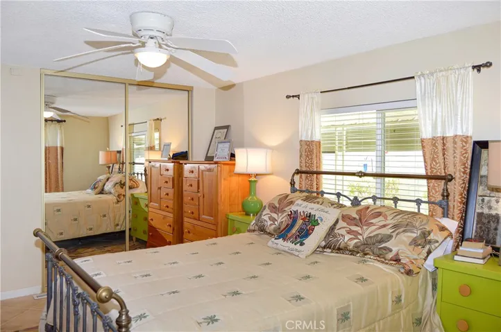 The main bedroom suite sits at the back of the home with a sliding door offering backyard access and desert views, a ceiling fan, tile flooring, and an en suite bath