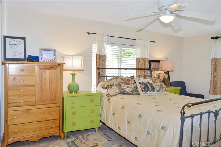 The main bedroom suite sits at the back of the home with a sliding door offering backyard access and desert views, a ceiling fan, tile flooring, and an en suite bath