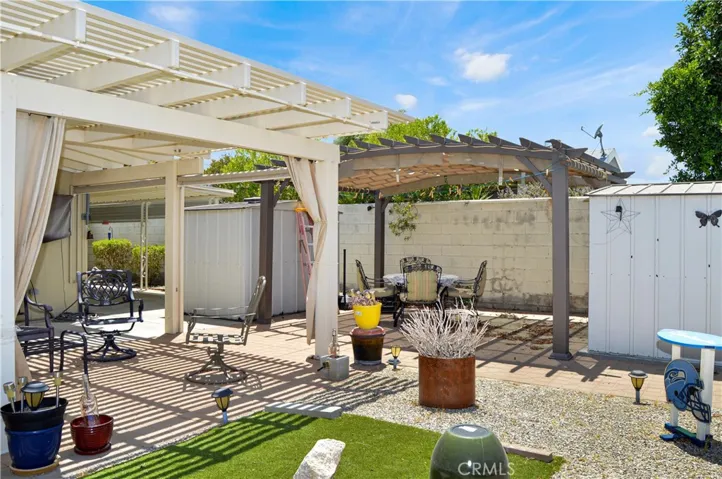 Back to that amazing backyard! Multiple covered patio provide the perfect spot to relax and enjoy the sweeping panoramic views of the desert landscape with distant mountains beyond with tall fences on both sides for privacy, artificial turf for your furry friends, easy-care rock scape, select greenery, and two large storage sheds which create a nook for the smaller patio