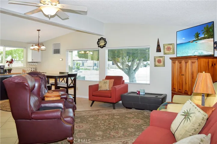 Spacious living room open to the dining area and kitchen with vaulted ceilings, tile floor, ceiling fan drywall-style walls for a modern feeling.