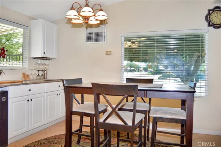 The dining area offers views of the front yard and neighborhood with extended kitchen cabinetry and a beverage fridge adjacent to it.