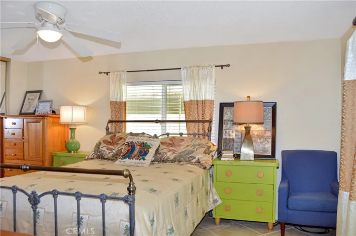 The main bedroom suite sits at the back of the home with a sliding door offering backyard access and desert views, a ceiling fan, tile flooring, and an en suite bath