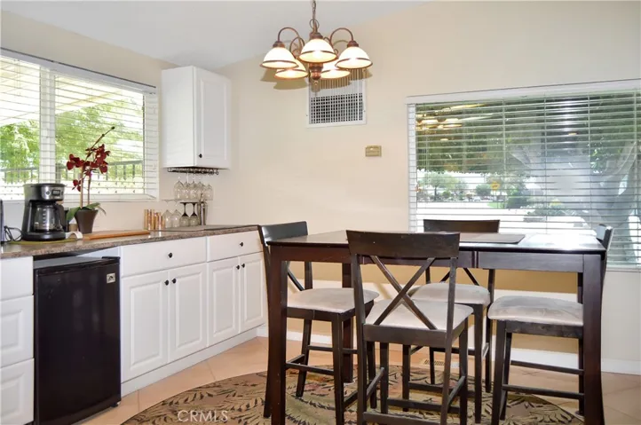 The dining area offers views of the front yard and neighborhood with extended kitchen cabinetry and a beverage fridge adjacent to it.