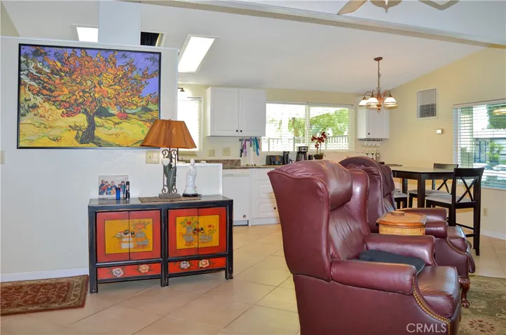 Spacious living room open to the dining area and kitchen with vaulted ceilings, tile floor, ceiling fan drywall-style walls for a modern feeling.