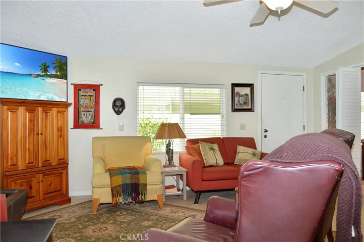 Spacious living room open to the dining area and kitchen with vaulted ceilings, tile floor, ceiling fan drywall-style walls for a modern feeling.