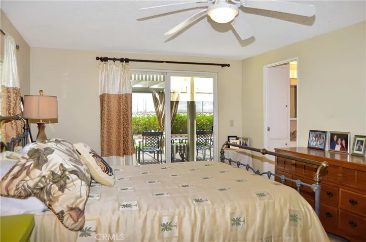 The main bedroom suite sits at the back of the home with a sliding door offering backyard access and desert views, a ceiling fan, tile flooring, and an en suite bath