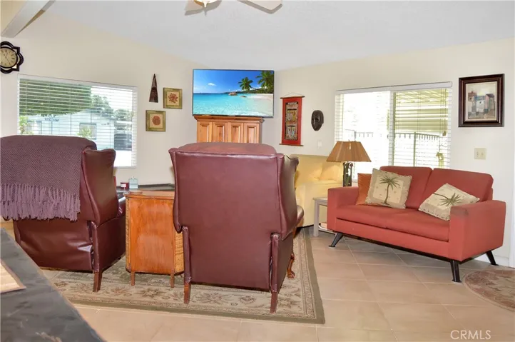 Spacious living room open to the dining area and kitchen with vaulted ceilings, tile floor, ceiling fan drywall-style walls for a modern feeling.