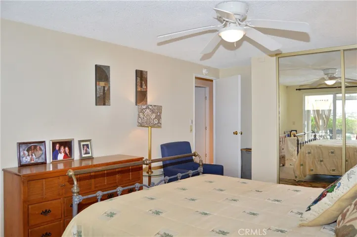 The main bedroom suite sits at the back of the home with a sliding door offering backyard access and desert views, a ceiling fan, tile flooring, and an en suite bath