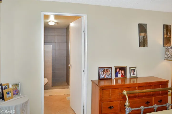 The main bedroom suite sits at the back of the home with a sliding door offering backyard access and desert views, a ceiling fan, tile flooring, and an en suite bath