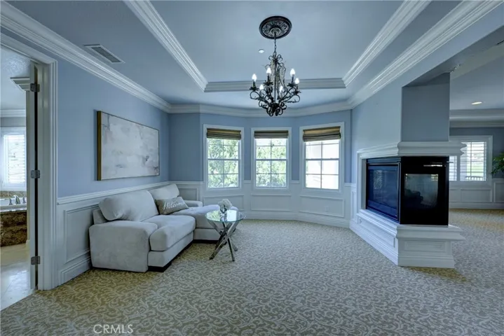Primary retreat is carpeted and has a beautiful chandelier.