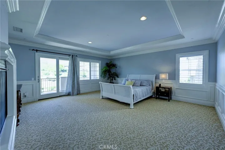 Expansive primary bedroom with coffered ceiling and slider to the private balcony.