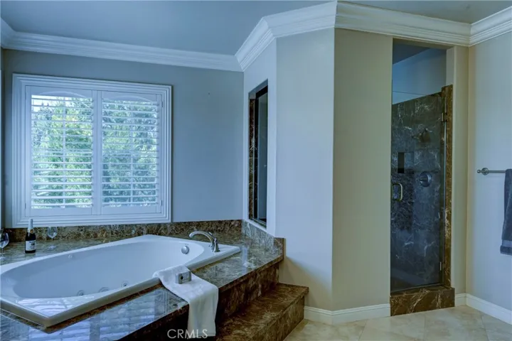This bright primary bath also has a roomy walk in shower and shutters on the windows.
