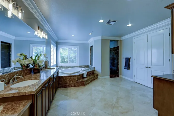 Double door entry to the primary bath, note the large crown molding and easy care flooring.