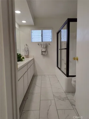 5 piece primary bathroom with newer marble flooring and shower surround
