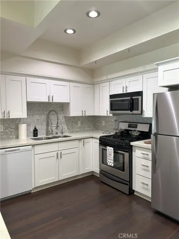 Kitchen with custom back splash, farmer faucet with double sinks and a gas stove, dishwasher, refrigerator, recessed lighting and spacious.