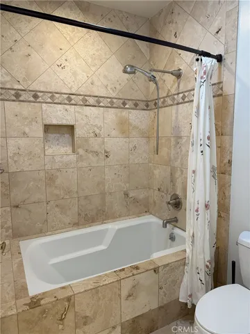 Primary bathroom with deep soaking tub which includes shower and incased in tile with a niche.