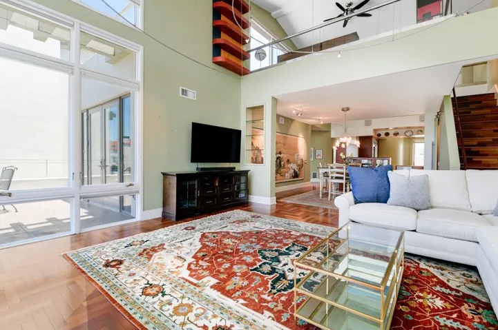 Living room with hardwood floors, dining room and kitchen and stairs to the loft and upper deck.