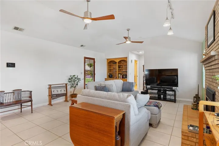Family Room: view from the kitchen, tile flooring, high vaulted ceiling, glass-paned door to rear patio & backyard at left rear.