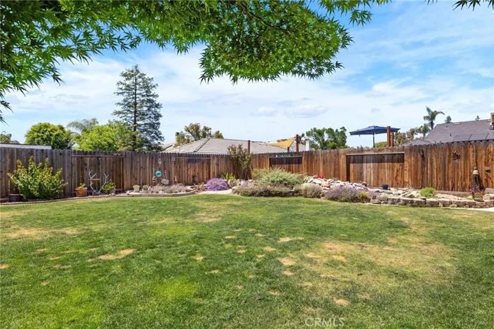 Backyard: view from patio, rock creek & pond water feature at right rear, wooden fences, automatic sprinklers & drip irrigation, flowerbed curbing, plenty of room for a pool.