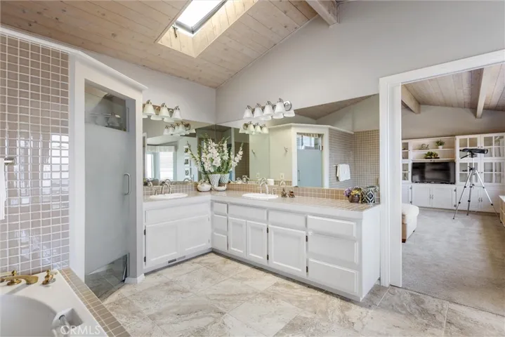 The upper level bathroom suite with tall ceilings, tile floors and lots of natural light via the skylight and windows. Glass enclosed water closet and spa tub. This space is just adjacent to the spacious loft.