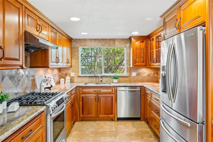 The Kitchen has been Upgraded with Granite Countertops, Travertine Backsplash with Mosaic Tile Inlay, Solid Wood Soft-Closing Custom Cabinetry with Glass Display Panels