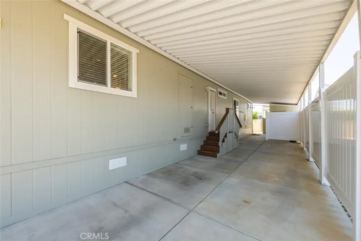 Spacious covered concrete carport with vinyl privacy fence.