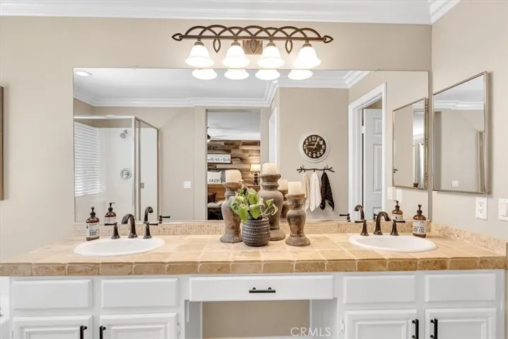 Freshly painted cabinets with contemporary black hardware, crown molding, Kohler sinks, and designer light fixture.