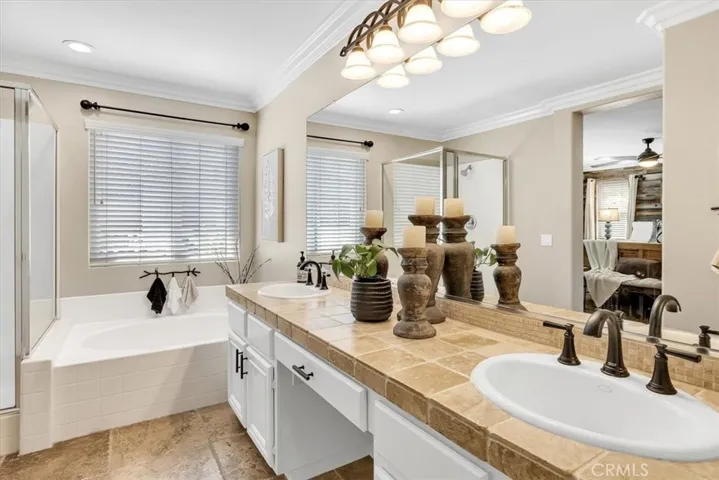 Primary ensuite offers dual sink vanity with tumbled stone countertop, freestanding soaking tub, separate walk-in shower, and spacious walk-in closet.
