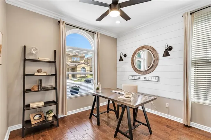 Ideal for guests or a home office, the main floor bedroom is coastal chic with shiplap accent wall, crown molding, designer lighting & ceiling fan.