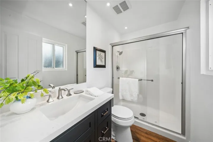 Ensuite includes walk-in shower w/ sliding glass doors & modernized stone countertop