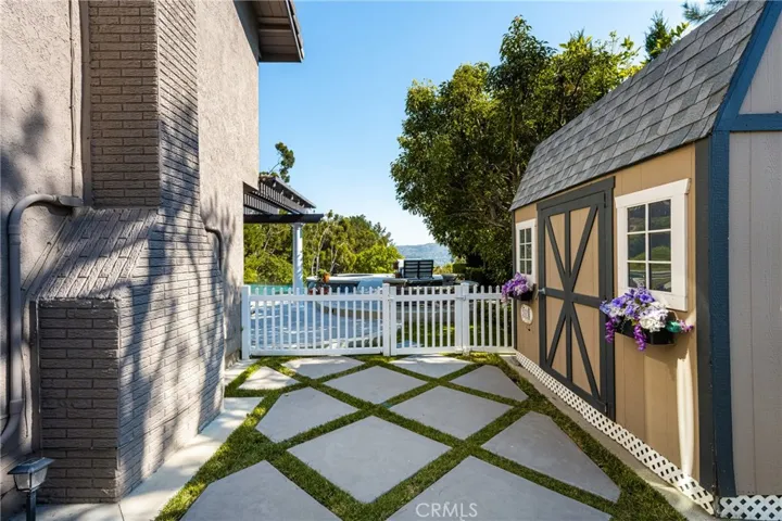 The fenced side yard features a shady area and a large Tuff Shed.