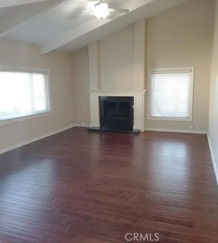 Spacious living room with a fireplace, skylight, ceiling fan, and distressed dark wood floors.