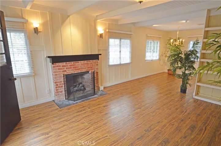 The living room with its gas fireplace, open beam ceiling, and mellow wood floors.