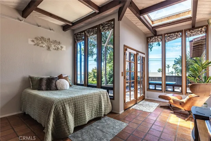 A primary suite with lots of light, tile flooring, high beamed ceiling and amazing views of the bay.