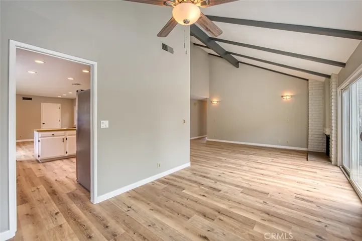Dining area and adjacent living room, both enhanced by vaulted beam ceiling.