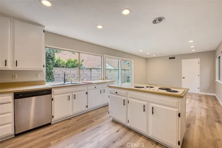 Kitchen boasts ample cabinet space and a convenient cooktop island, seamlessly flowing into the family room.
