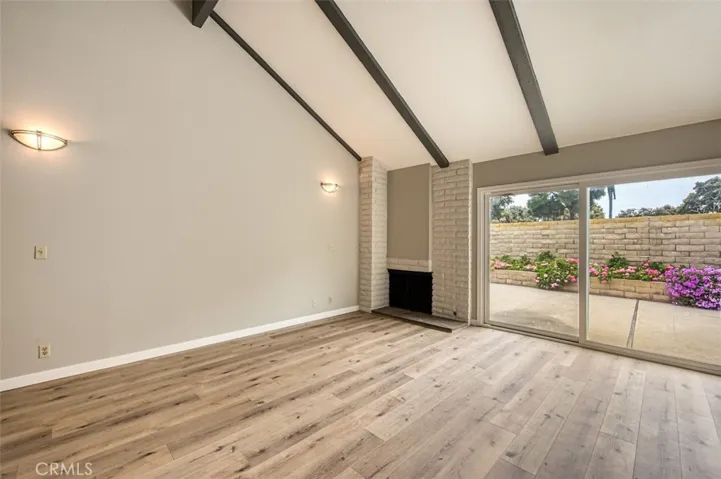 Living room with cozy fireplace, windows galore and enhanced by vaulted beam ceiling.