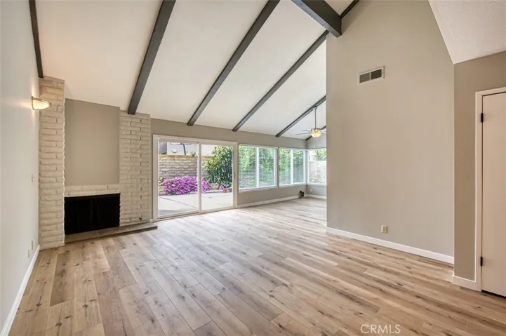 Living room with cozy fireplace and enhanced by vaulted beam ceiling.
