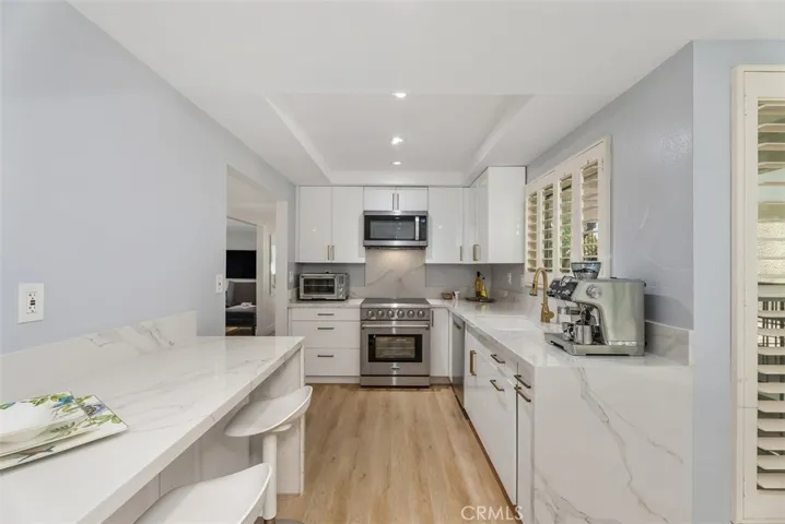 View of seating island in kitchen on left with kitchen nook nearby on the right