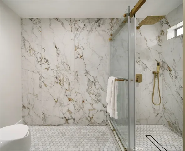 Marble tiled floors and porcelain tile walls in primary bathroom