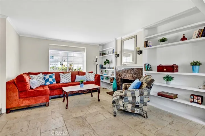 Formal Living Room with Tumbled Marble Flooring, Marble Fireplace, Custom built-In Shelving, and French Dual Pane Windows