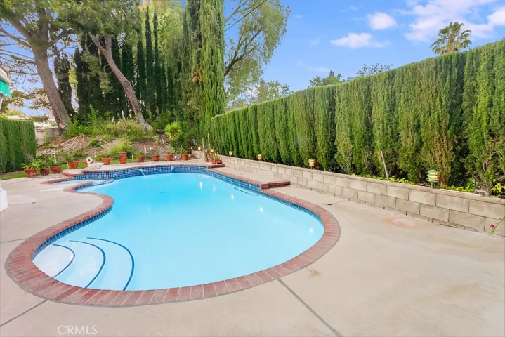 The secluded backyard will be a favorite entertainment destination with its sparkling in-ground heated fiberglass lined pool and spa, new pool light, grassy areas, shaded open patio, towering privacy and shade trees, colorful flowerbeds, remote controlled electric awnings that shades the house, handy garden shed, PLUS a convenient poolside outdoor bathroom with vanity, dressing mirror, storage shelves, commode and tiled floors.